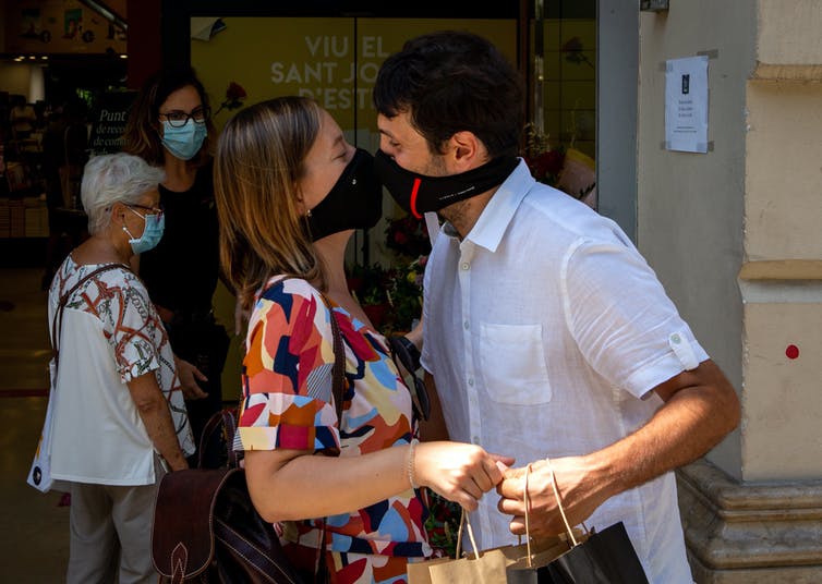 A couple wearing face masks kiss in Barcelona.