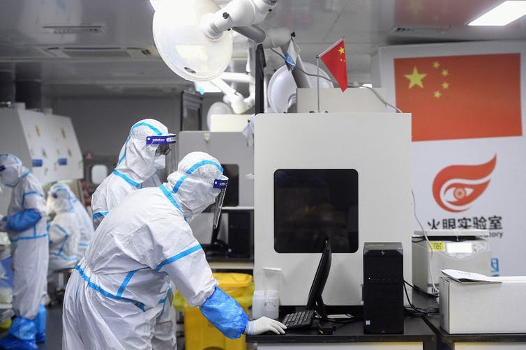 Des techniciens en tenues protectrices travaillent sur des échantillons dans un laboratoire de Wuhan
