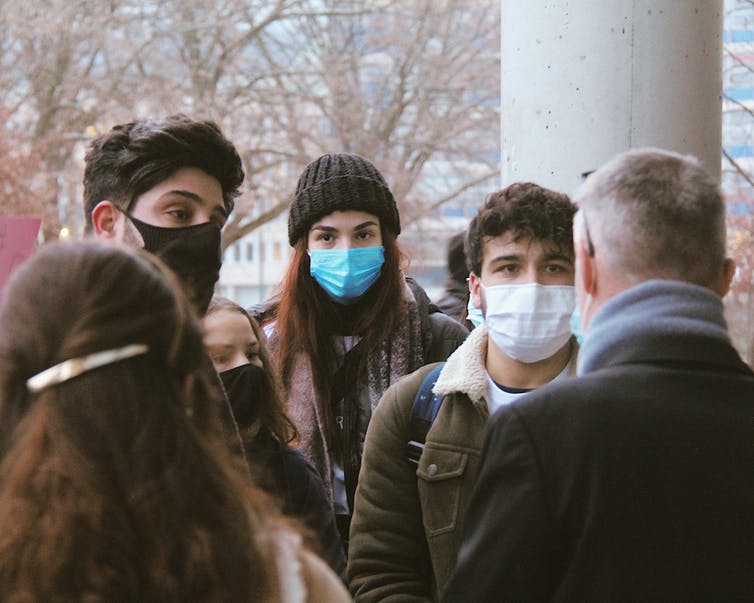Jeunes gens portant des masques en train de discuter à l’extérieur.